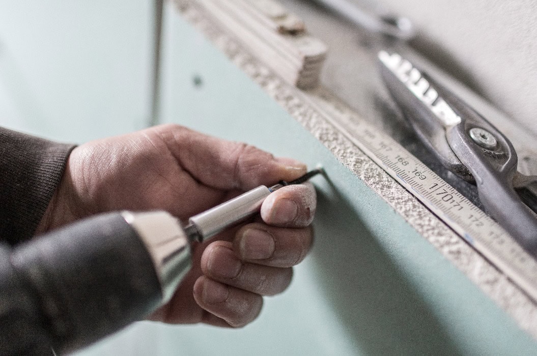 Eine Rigipsplatte wird mit Bohrmaschine und Schraube befestigt